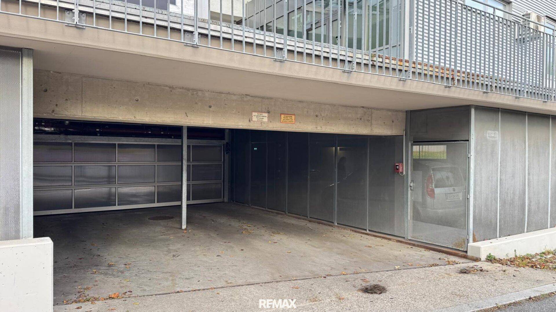 Offene Parkgarage unter einem Gebäude mit mehreren Stellplätzen und Zufahrt.