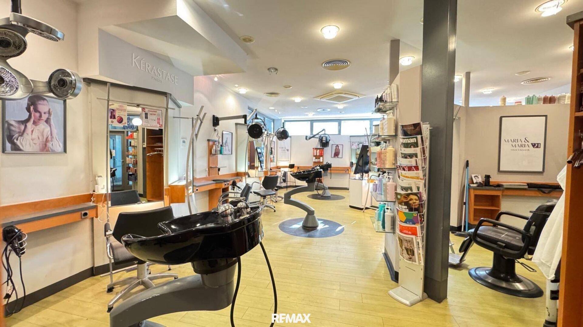 Geräumiger Friseursalon mit mehreren Styling-Stationen, Waschbecken und Produktregalen.