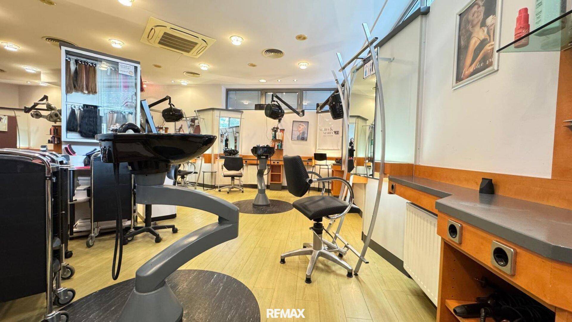 Friseursalon mit Waschbecken, Styling-Stühlen und Blick auf weitere Arbeitsbereiche.
