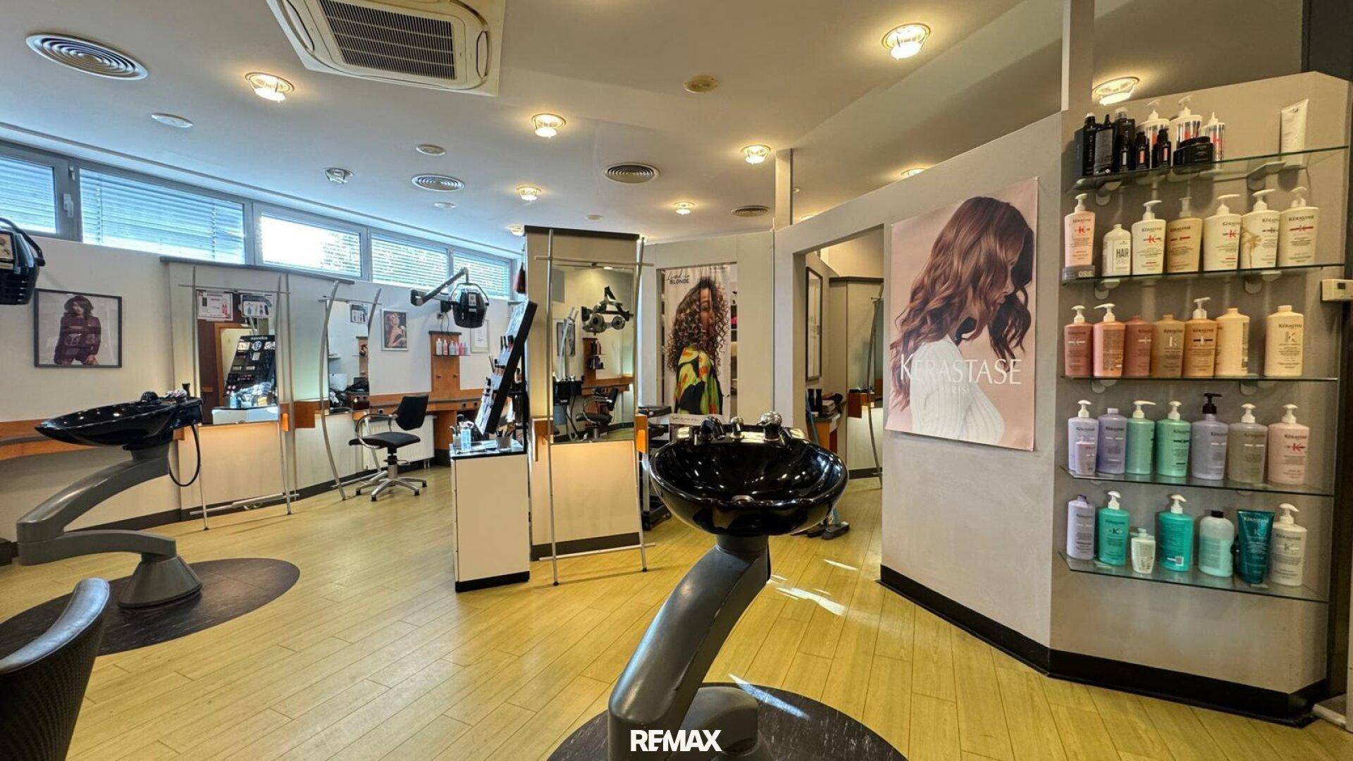 Heller Friseursalon mit zahlreichen Arbeitsplätzen, großen Fenstern und Klimaanlage.
