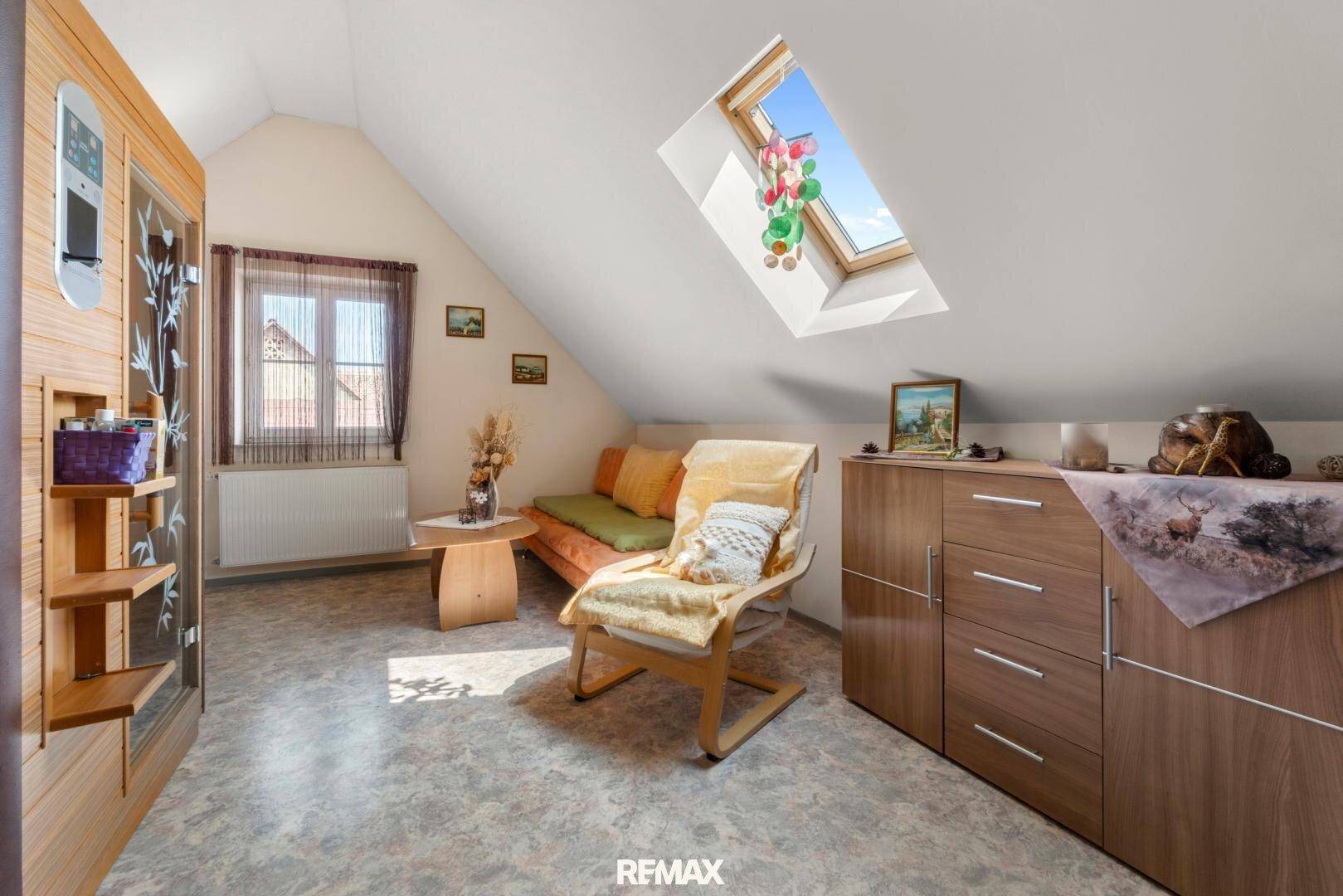 Entspannungsbereich im Dachgeschoss mit Sauna, Sitzgelegenheiten und Dachfenster.
