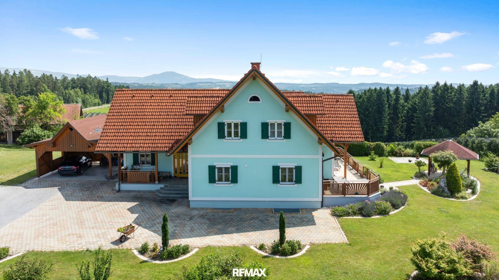 Freistehendes Einfamilienhaus mit weitläufigem Garten, Carport und Bergblick in ländlicher Umgebung.