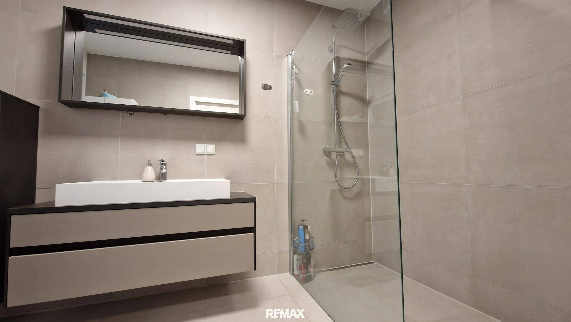 Modernes Badezimmer mit schwebendem Waschtisch, Einzelwaschbecken und begehbarer Dusche.