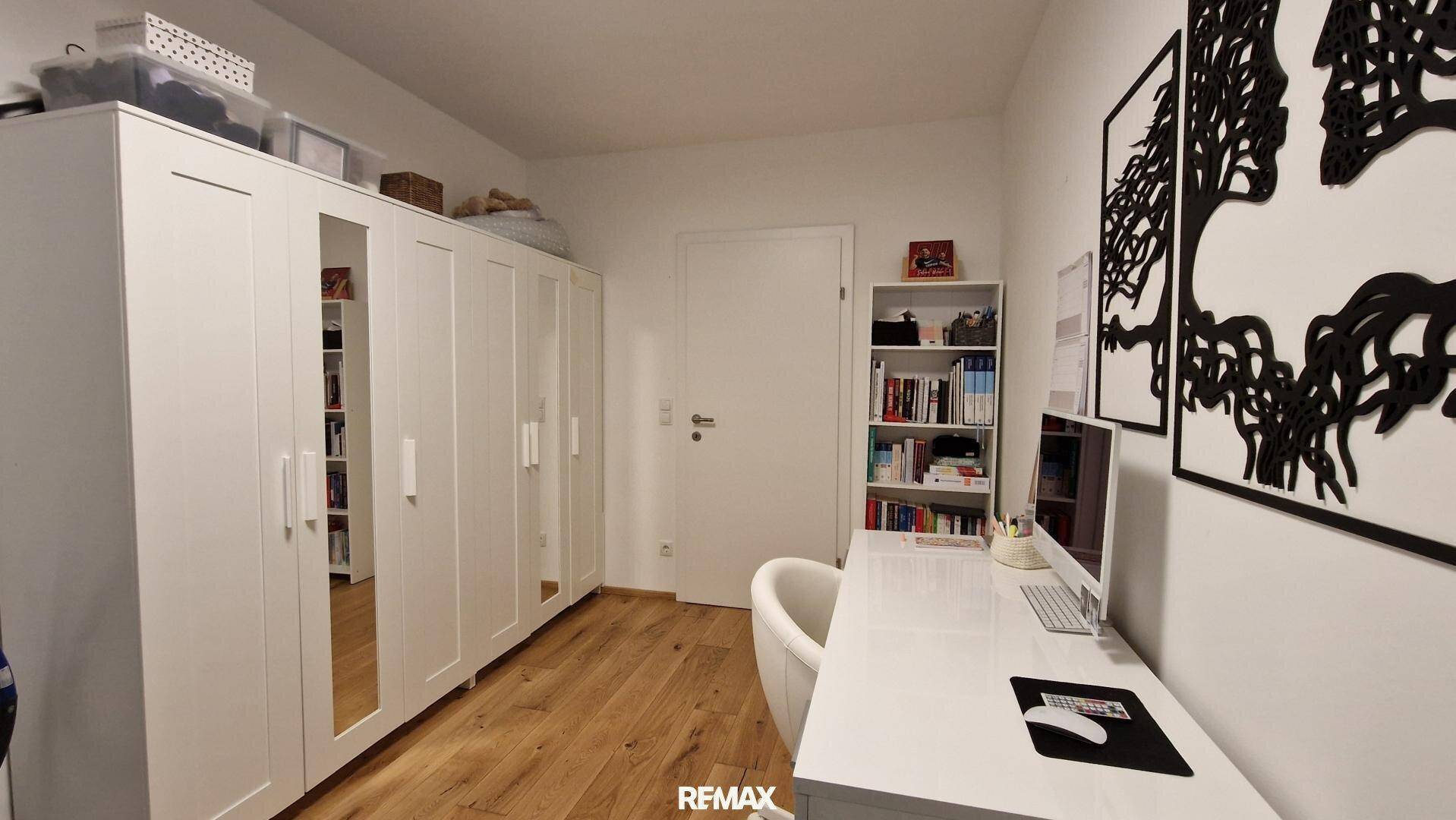Geräumiges Büro mit großem weißen Kleiderschrank, Bücherregalen und Holzboden.