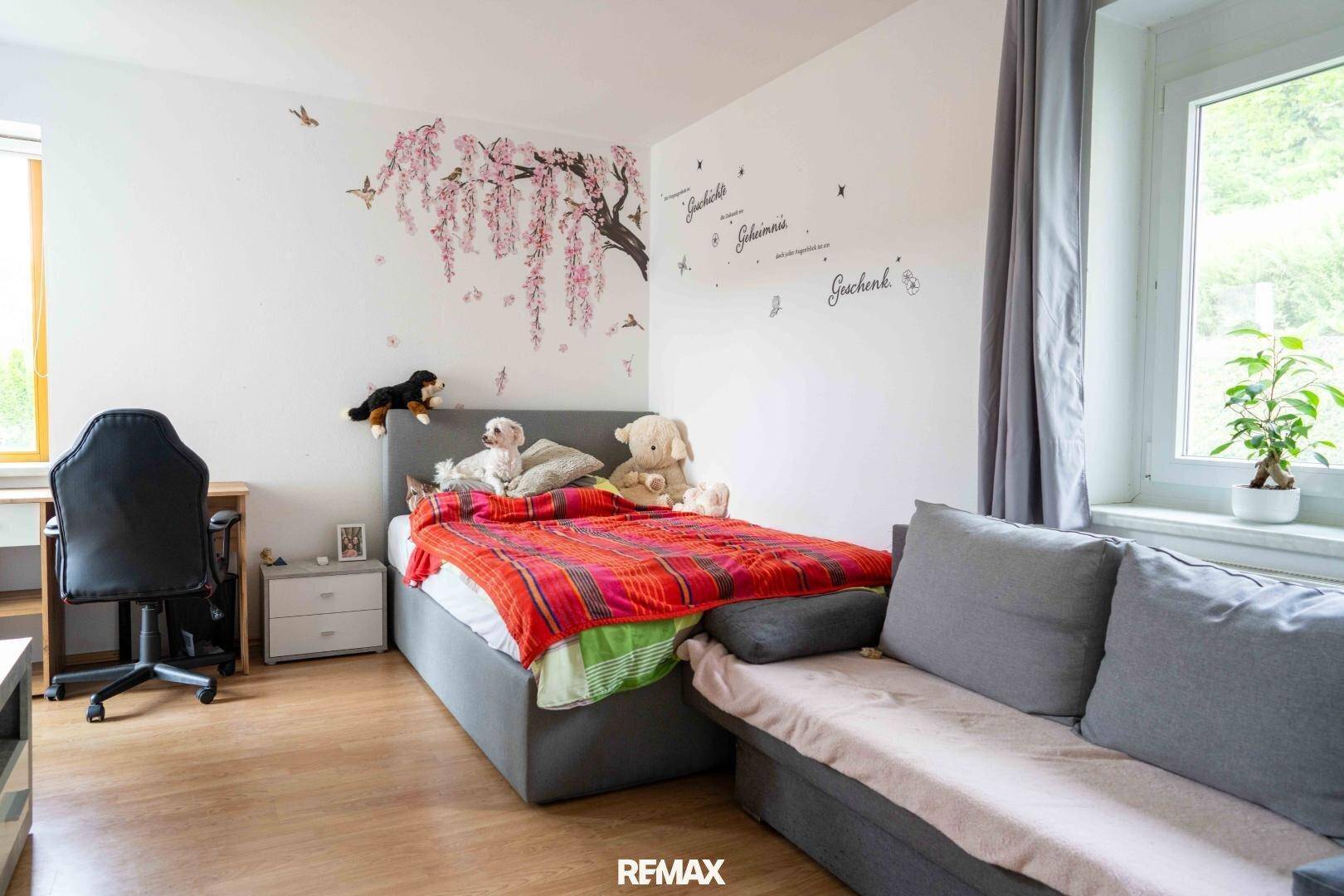 Helles Schlafzimmer mit Einzelbett, Schreibtisch und verspielter Wanddekoration.