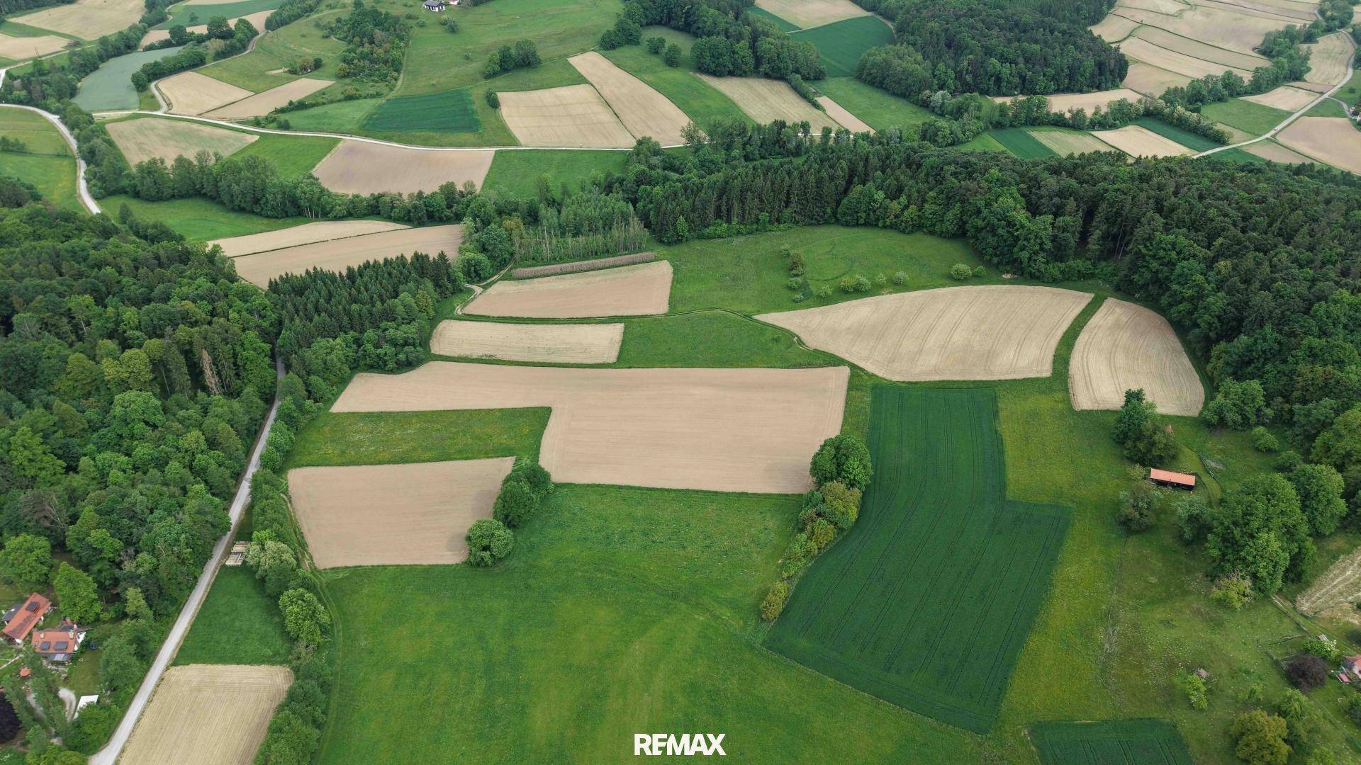 Luftaufnahme einer abwechslungsreichen Agrarlandschaft mit Feldern, Wäldern und ländlichen Wegen.
