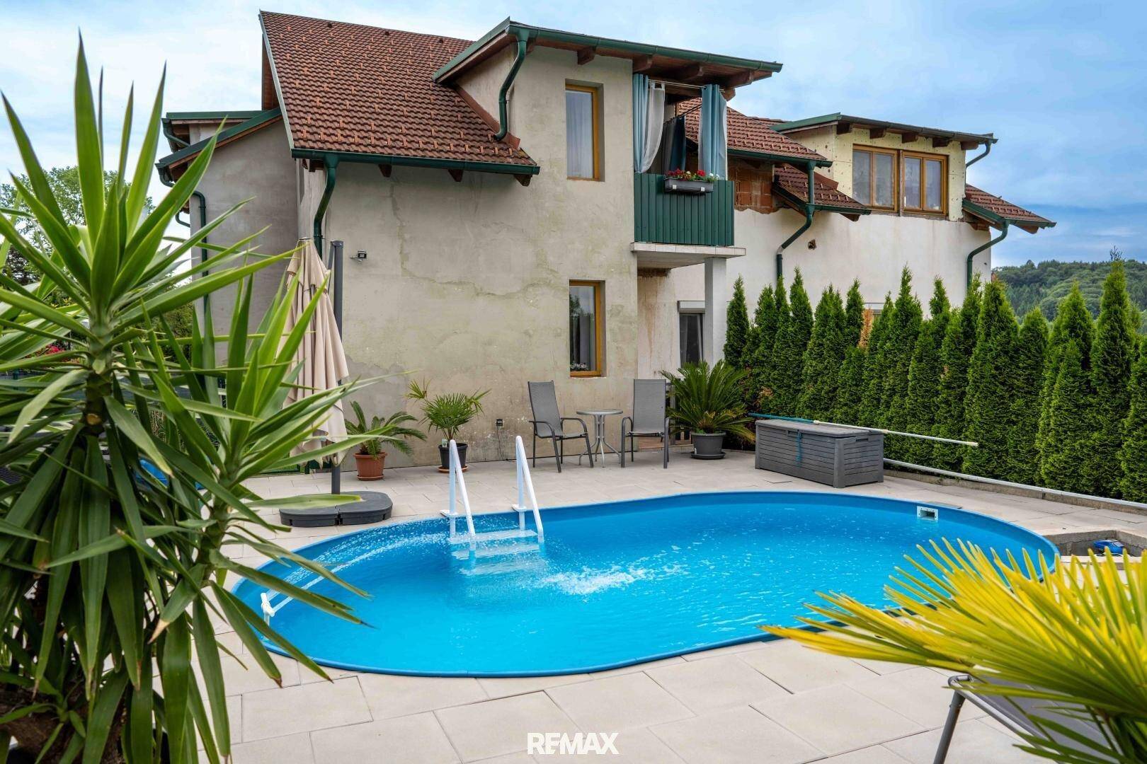 Außenbereich mit ovalem Pool, gepflasterter Terrasse und mediterranen Pflanzen.