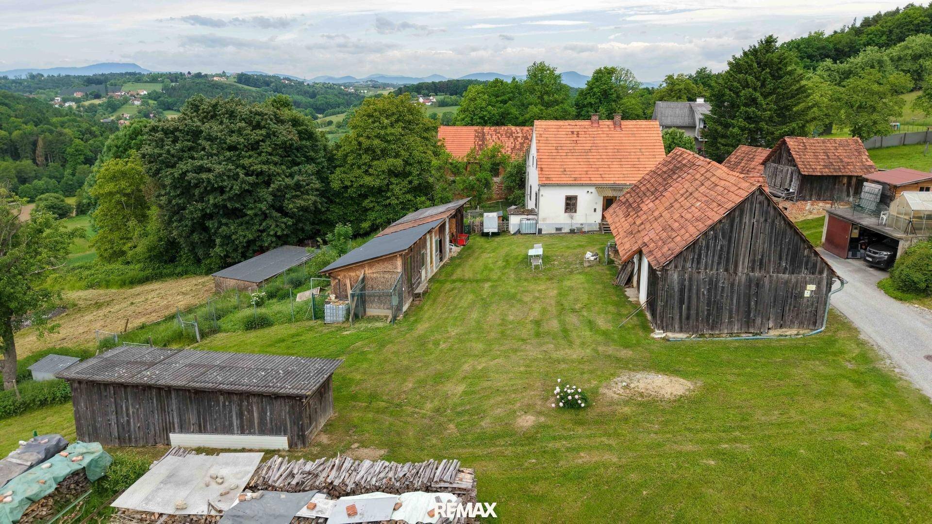 Luftaufnahme eines Bauernhofs mit Scheunen und weitläufigen Grünflächen in ländlicher Umgebung.