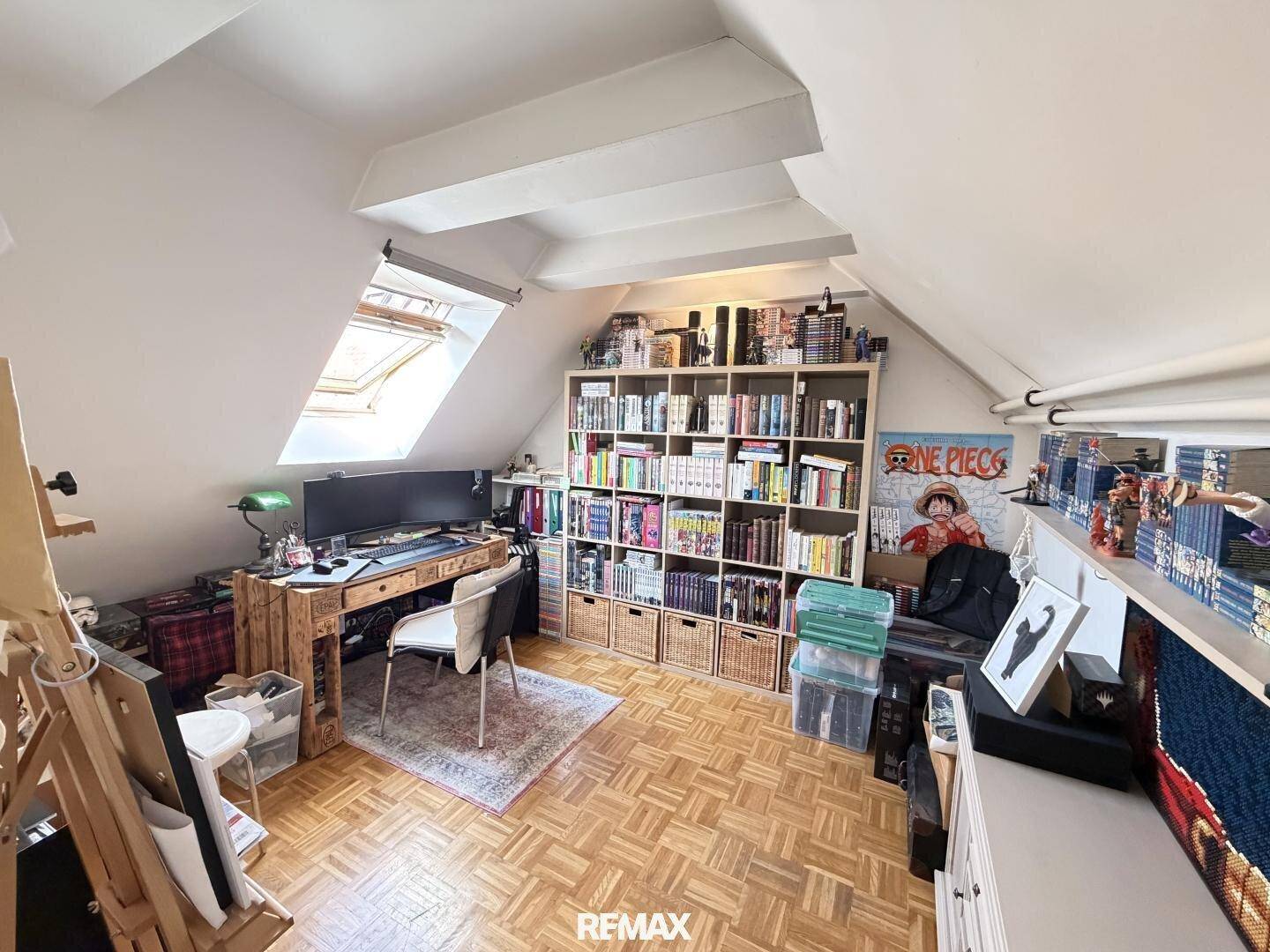 Dachgeschoss-Büro mit Schreibtisch, Bücherregal, Dachfenster und Parkettboden, hell und funktional.