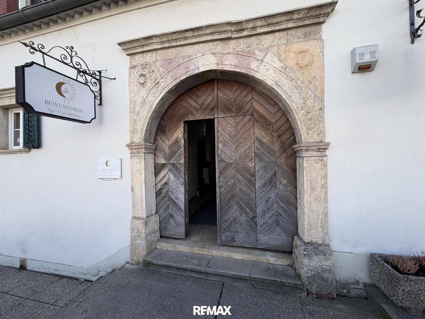 Detailansicht des beeindruckenden, bogenförmigen Holztors mit Steinfassung und historischer Architektur.