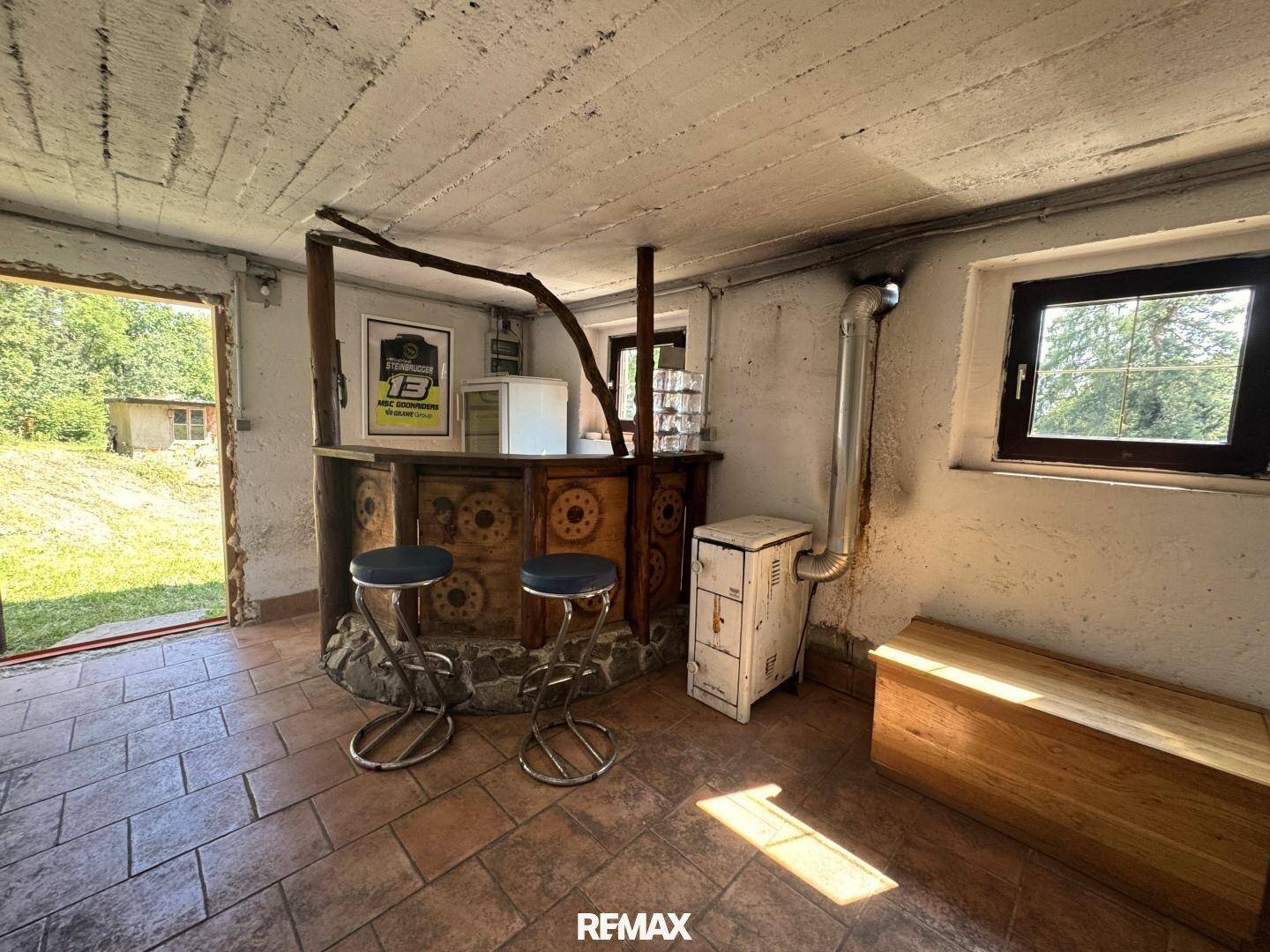 Kellerraum mit Bar, gefliestem Boden und Fenster, ideal als Freizeitbereich.