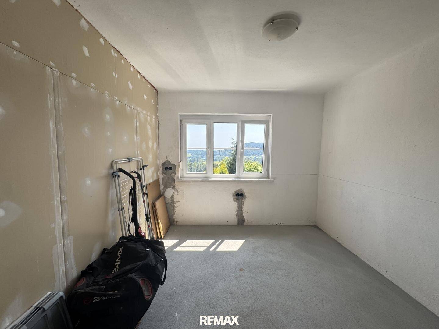 Raum im Rohbau mit Gipskartonwänden und einem Fenster mit Ausblick.