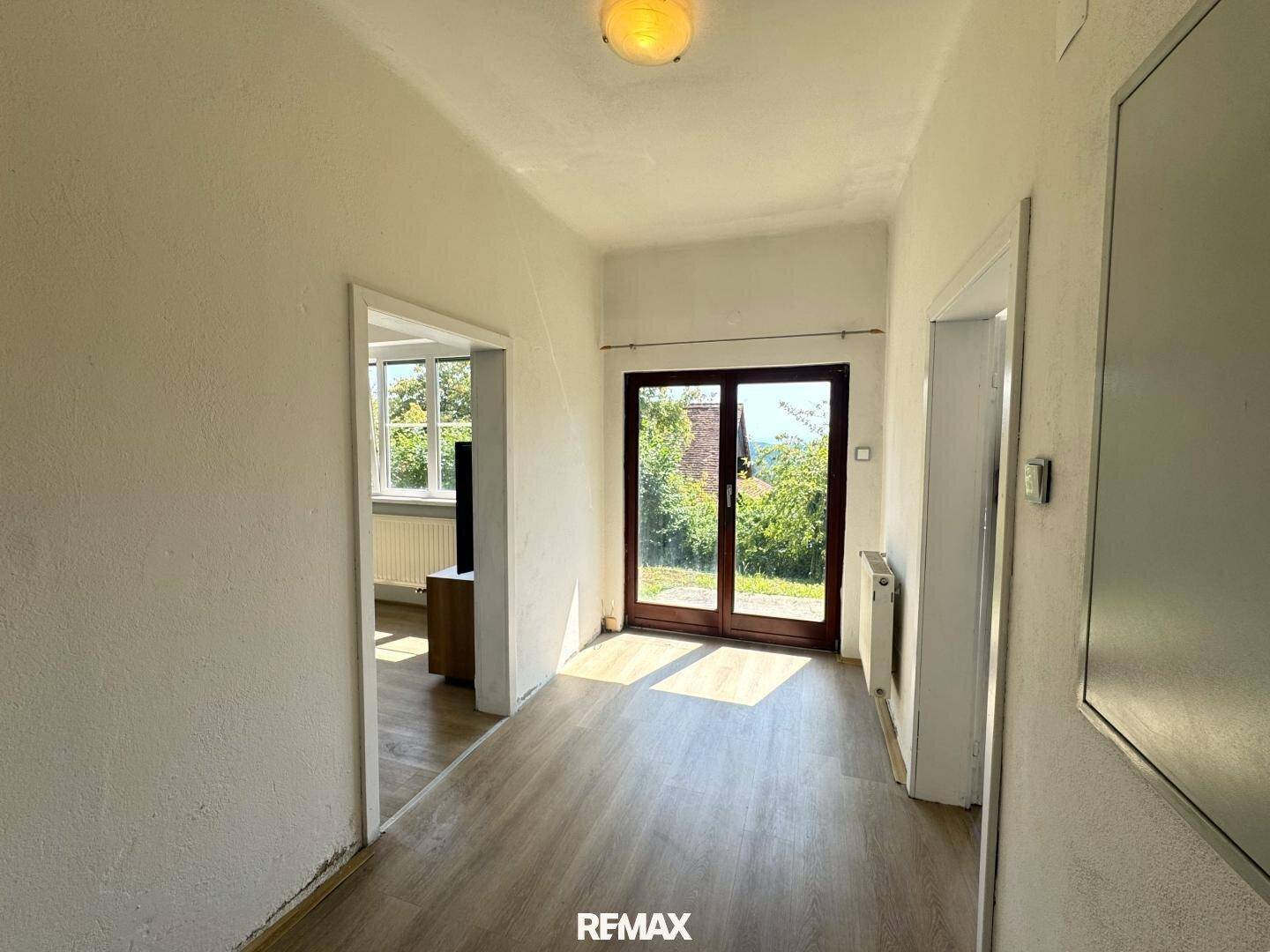 Heller Flur mit Zugang nach draußen und Verbindung zu weiteren Räumen im Haus, lichtdurchflutet.