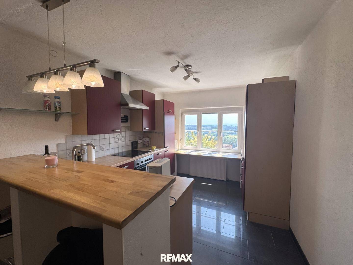 Küche mit dunklen Schränken, Holzarbeitsplatte und einem Fenster mit Ausblick, ideal für Mahlzeiten.