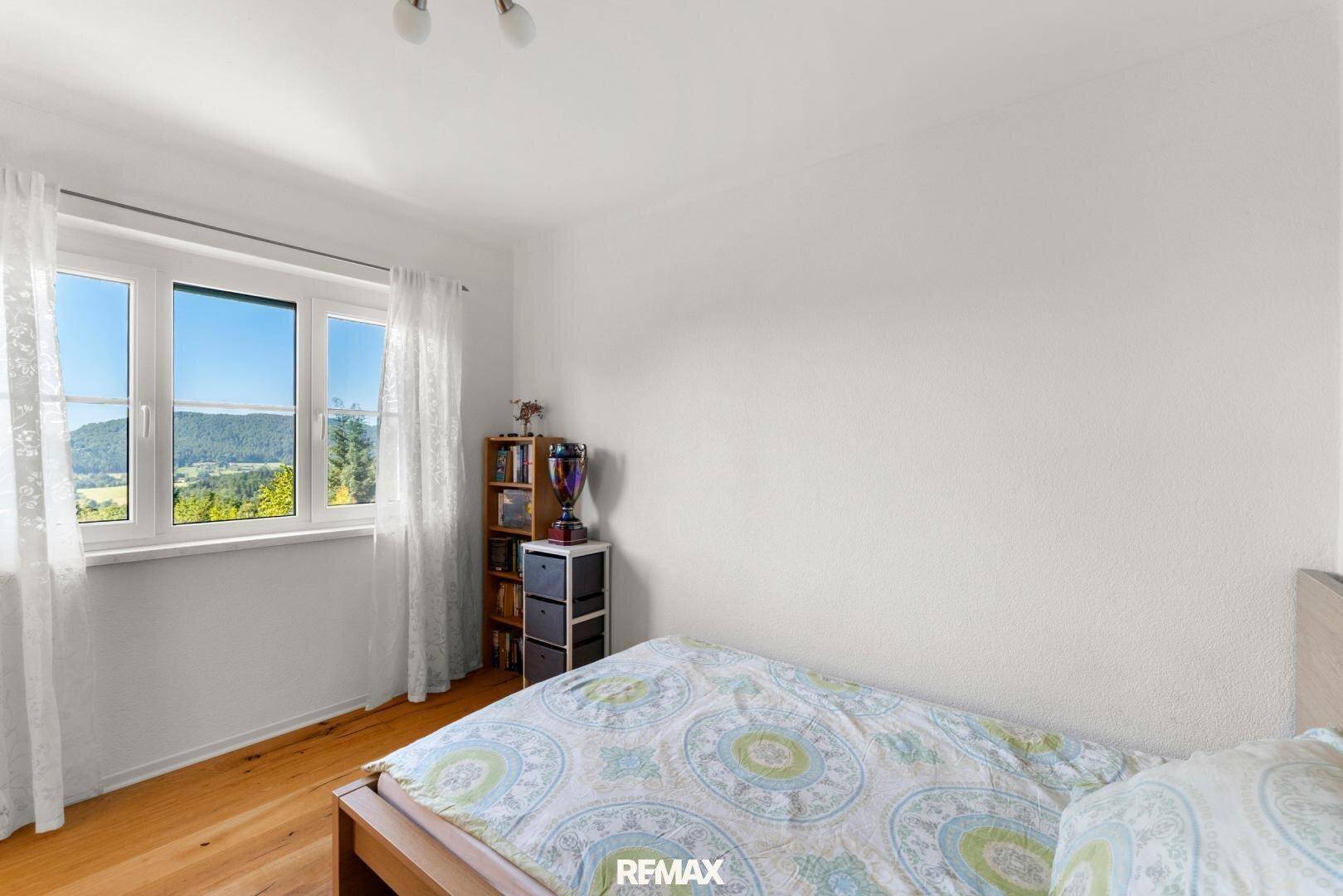 Schlafzimmer mit Einzelbett und Fenster, das einen schönen Blick auf die umliegende Landschaft bietet.