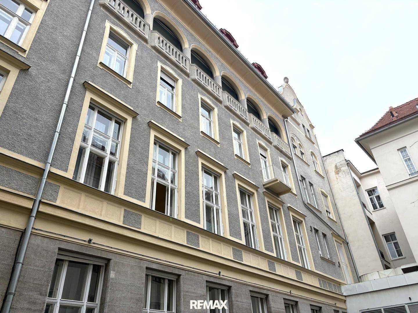 Historische Fassade eines Gebäudes mit vielen Fenstern und dekorativen Balkonen unter einem bewölkten Himmel.