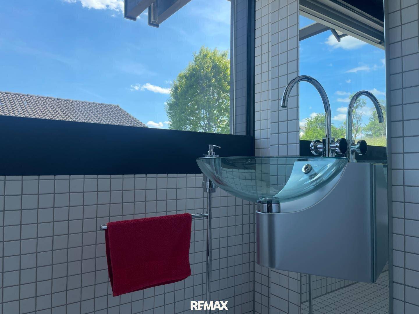 Detailansicht des modernen Design-Waschbeckens im Gäste-WC mit kleinen weißen Fliesen.