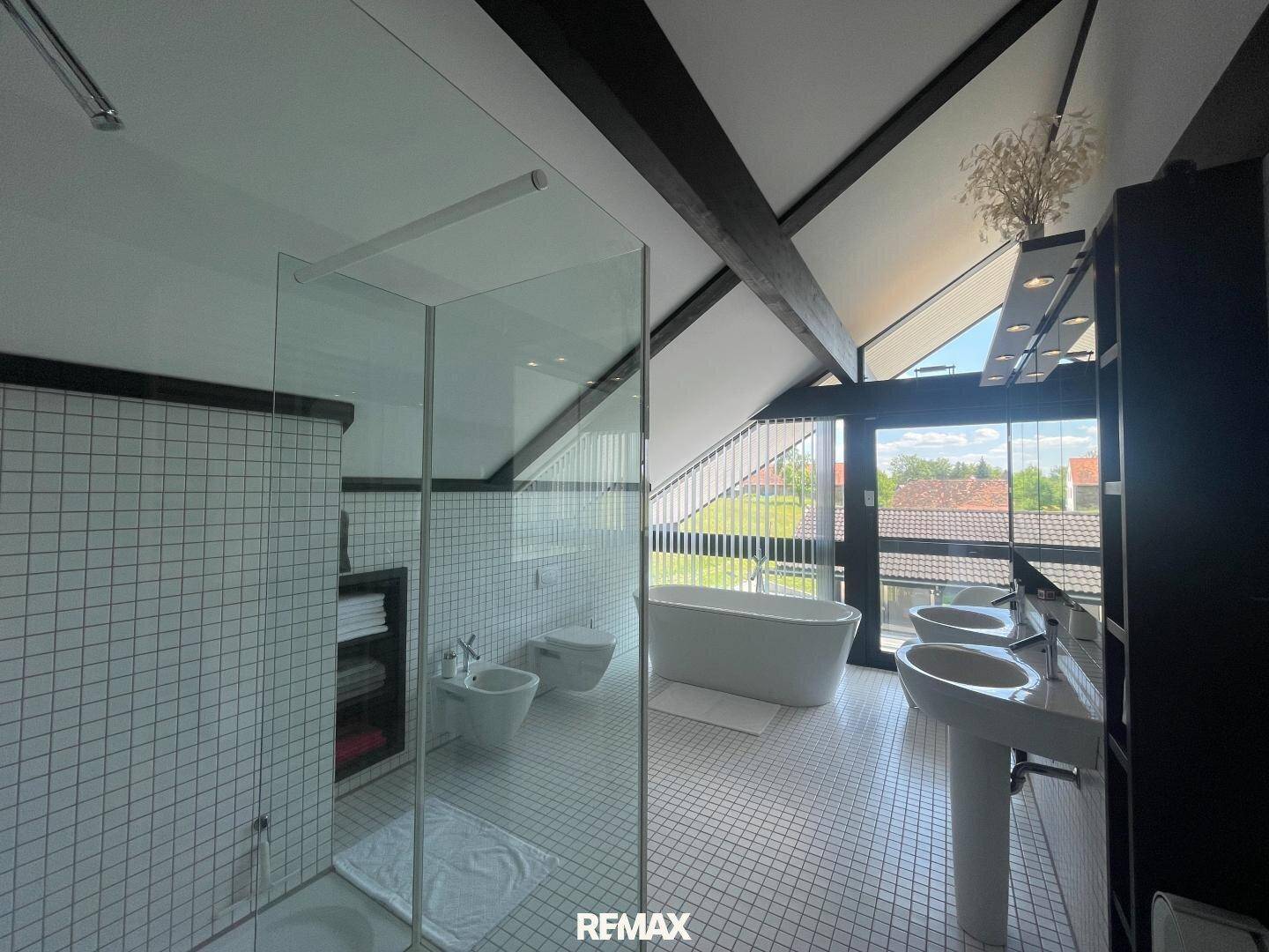 Großes Badezimmer im Dachgeschoss mit freistehender Badewanne, Doppelwaschbecken und begehbarer Dusche.