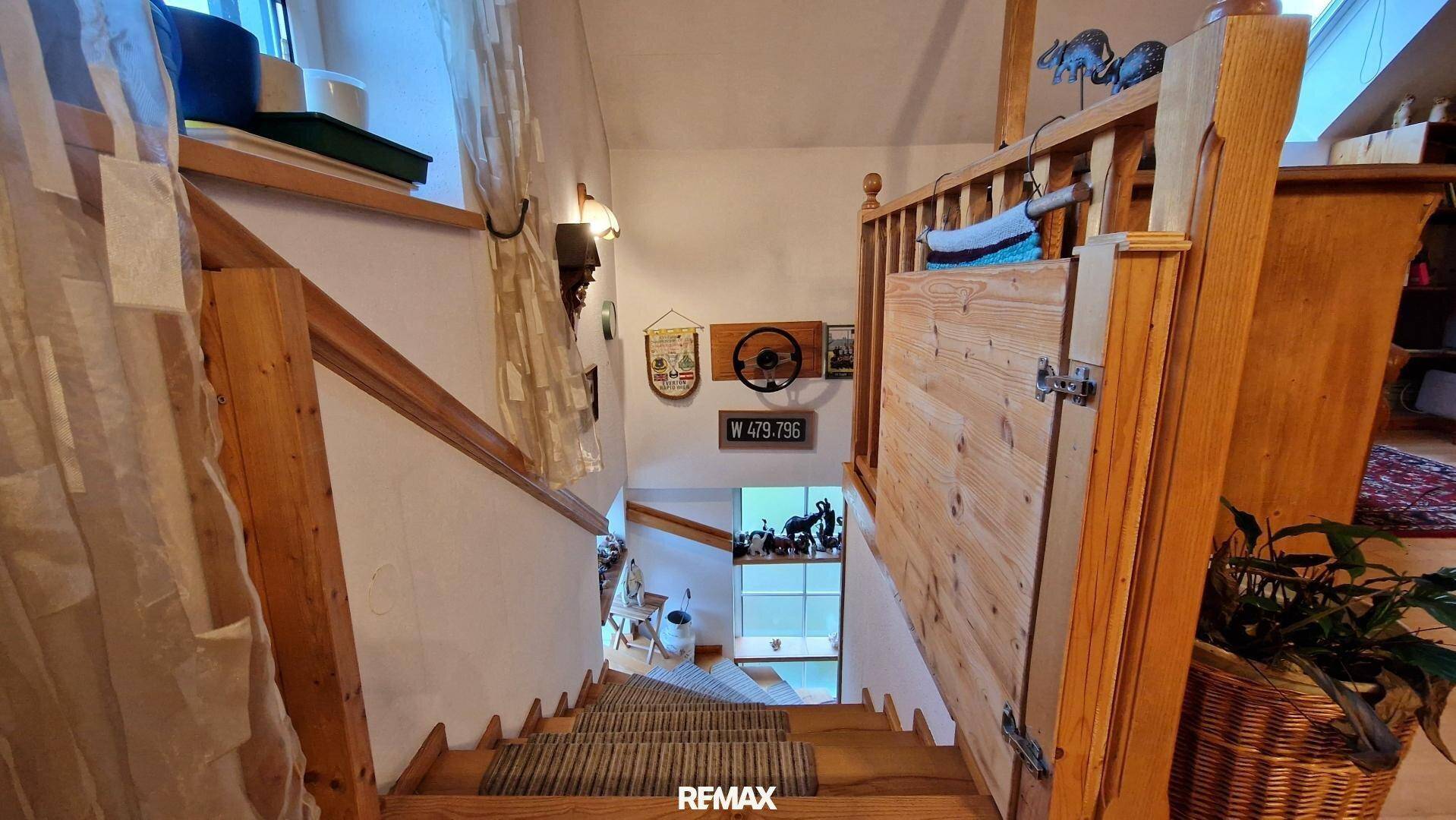 Holztreppe mit Teppichläufern und traditionellen Dekorationen, die die Stockwerke verbindet.