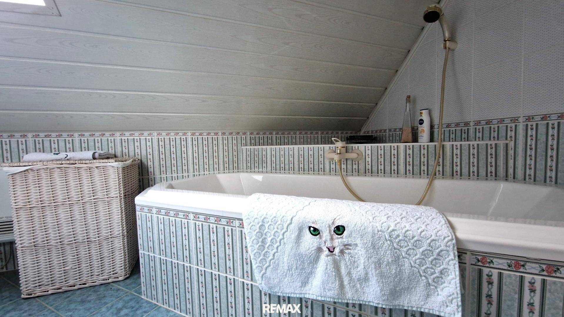 Badezimmer mit Badewanne und gefliesten Wänden im traditionellen Stil.