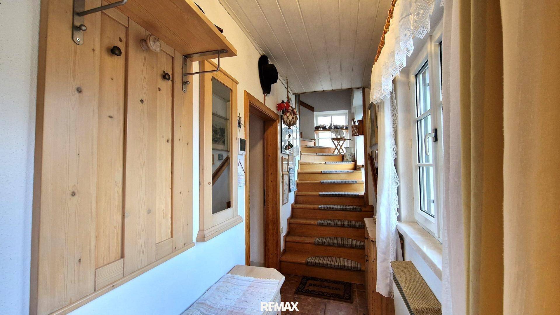 Heller Flur mit Holzvertäfelung und einer Holztreppe, die in die oberen Stockwerke führt.