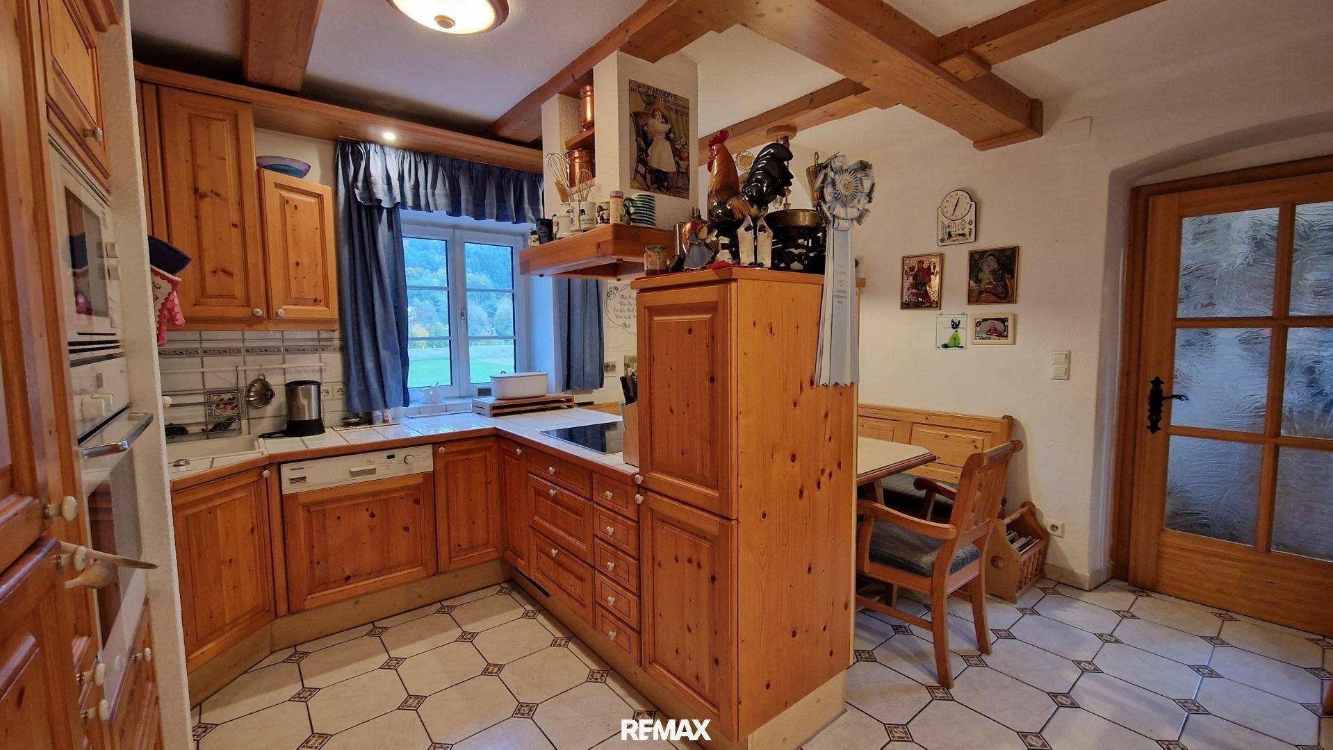 Gemütliche Holzküche im Landhausstil mit Fliesenboden und sichtbaren Deckenbalken.