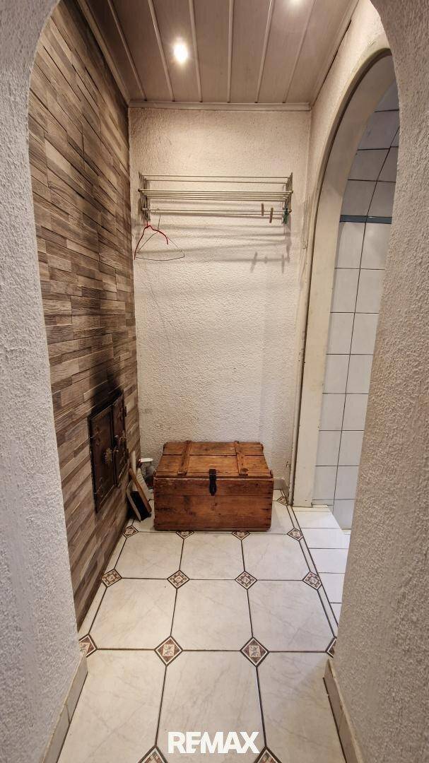 Kleiner Flur oder Hauswirtschaftsraum mit Fliesenboden und Holzwandverkleidung.