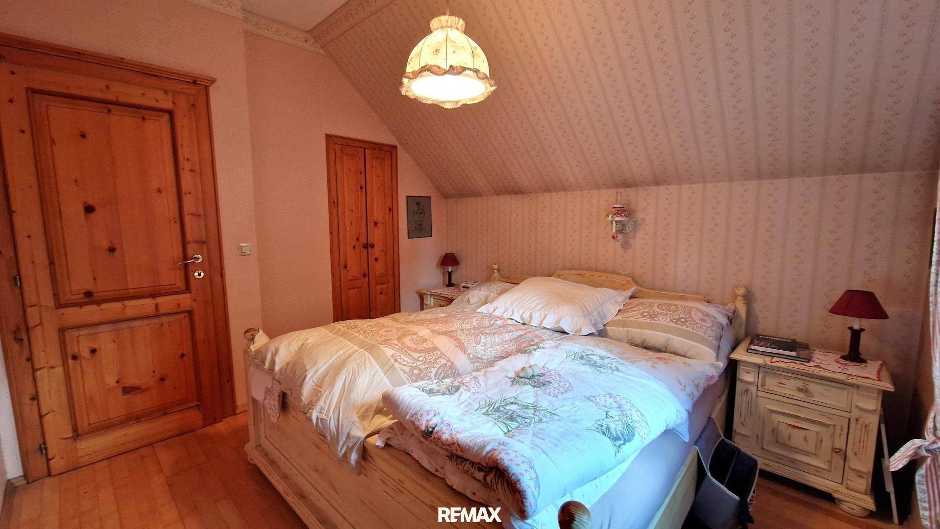 Schlafzimmer mit Holztüren, Doppelbett und Nachttischen im traditionellen Stil.