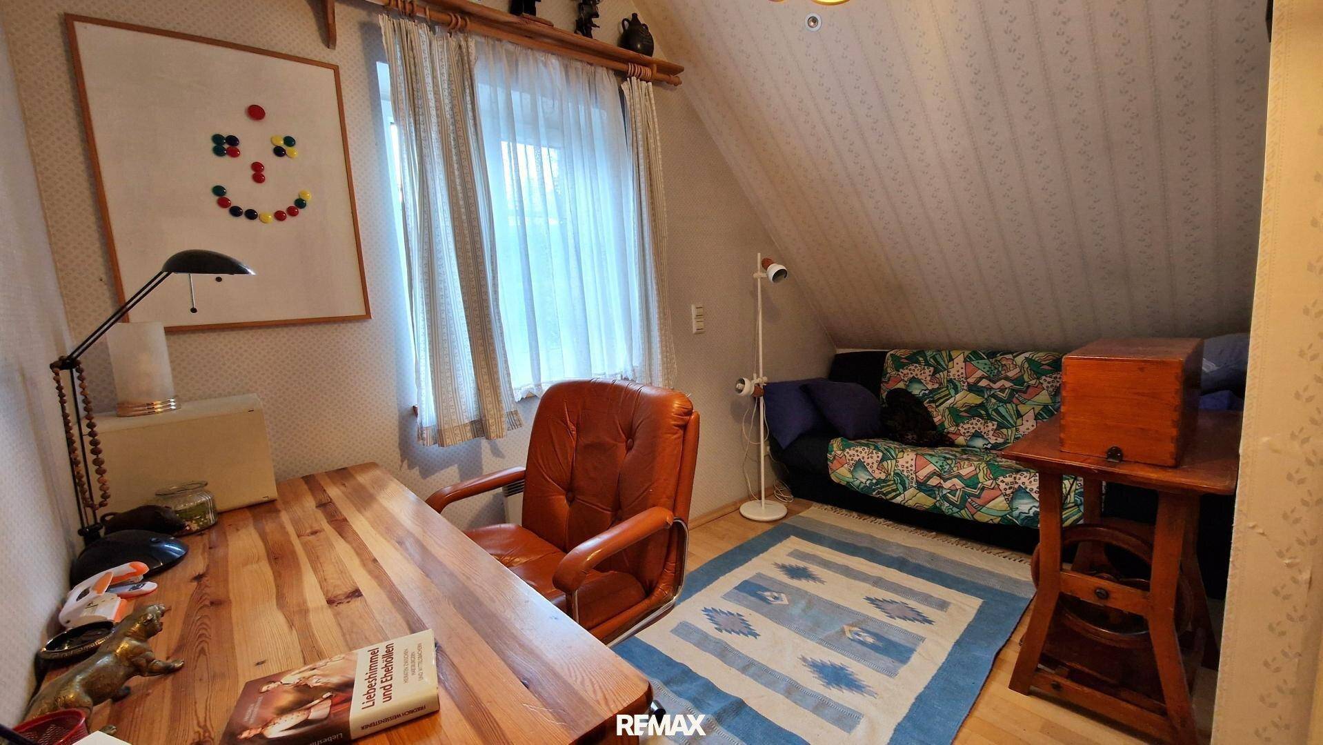 Kleines Arbeitszimmer oder Gästezimmer im Dachgeschoss mit Schreibtisch und Sofa.