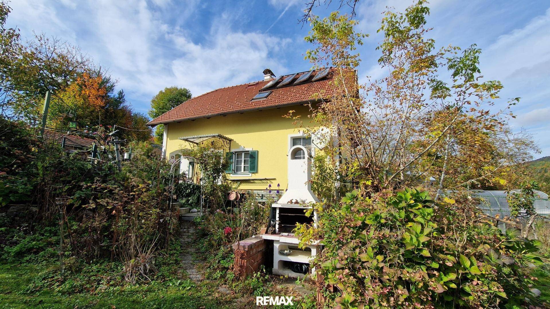 Rückseite des Hauses mit Garten, Grillplatz und üppiger Vegetation.