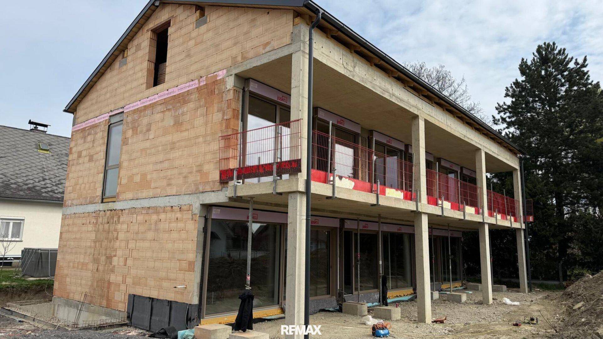 Rohbau eines modernen Hauses mit Ziegelwänden und vorbereiteten Balkonbereichen.
