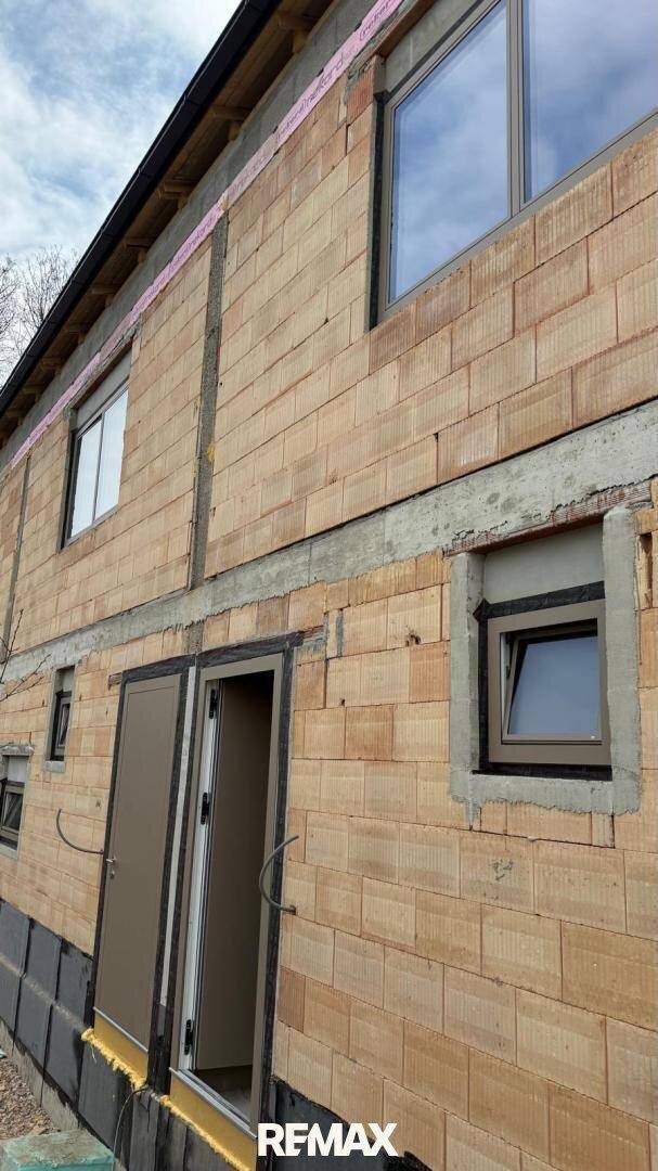 Detailansicht der Ziegelmauer eines im Bau befindlichen Hauses mit Fensteröffnung.