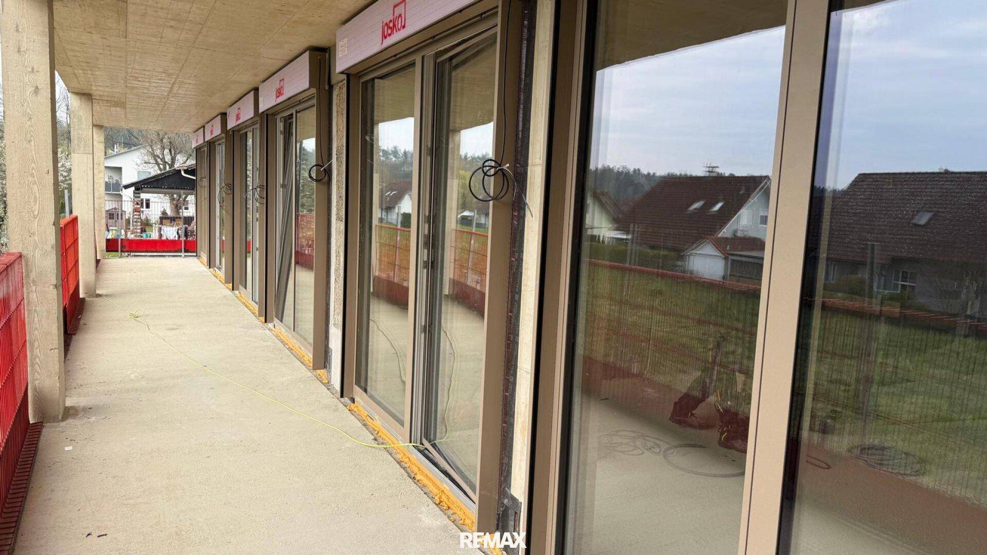 Langer Balkon im Rohbau mit großen Schiebetüren zum Innenbereich des Hauses.