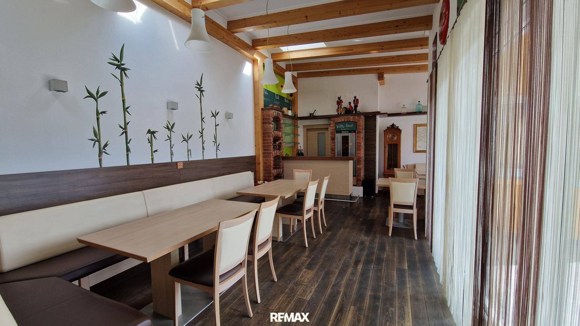 Gemütlicher Restaurant-Essbereich mit Holztischen, Bänken und sichtbaren Deckenbalken, hell und einladend.