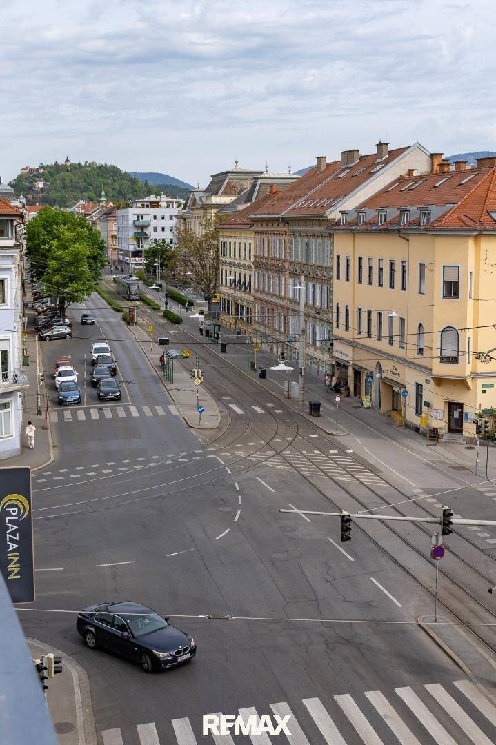 Weitläufige Stadtansicht mit Straßen, Gebäuden und Fahrzeugen unter bewölktem Himmel.