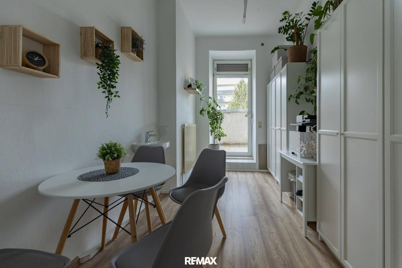 Heller Essbereich mit rundem Tisch, modernen Stühlen und Schränken, mit Zugang zu einem Balkon.