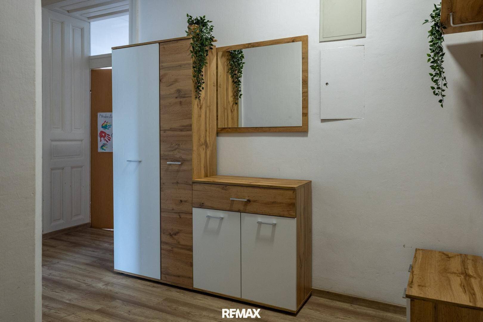 Heller Flur mit modernem Garderobenschrank aus Holz und Spiegel, dekoriert mit Pflanzen.