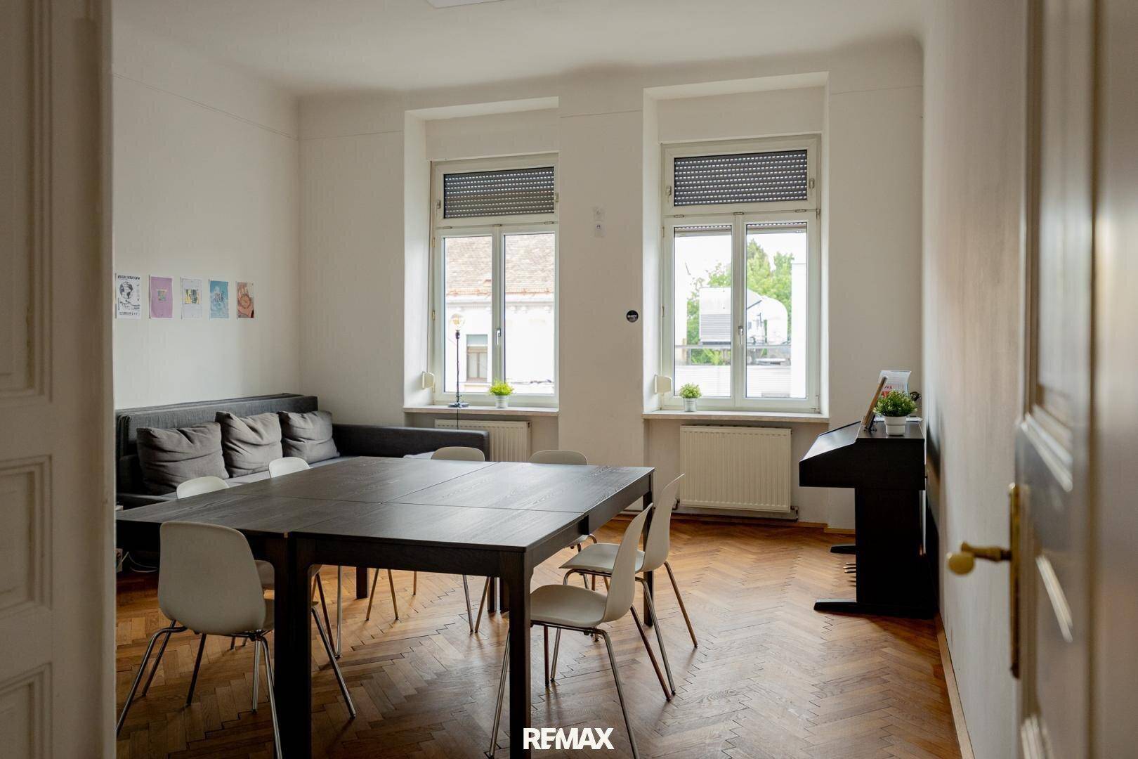 Geräumiger Essbereich mit großem Tisch, Stühlen und Klavier, mit Blick durch große Fenster.
