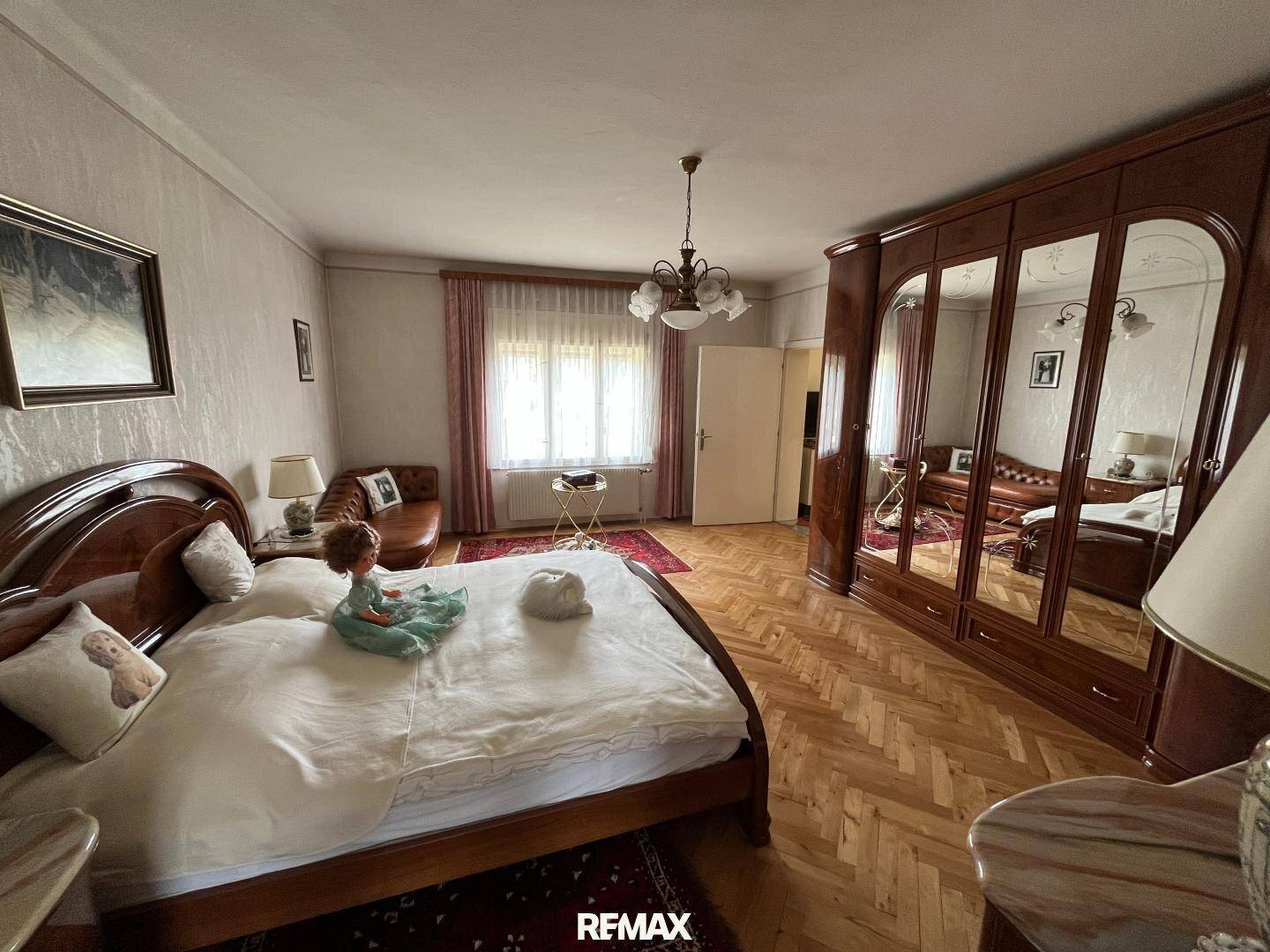 Gemütliches Schlafzimmer mit Holzparkett, großem Bett und Spiegelschrank in traditionellem Stil.