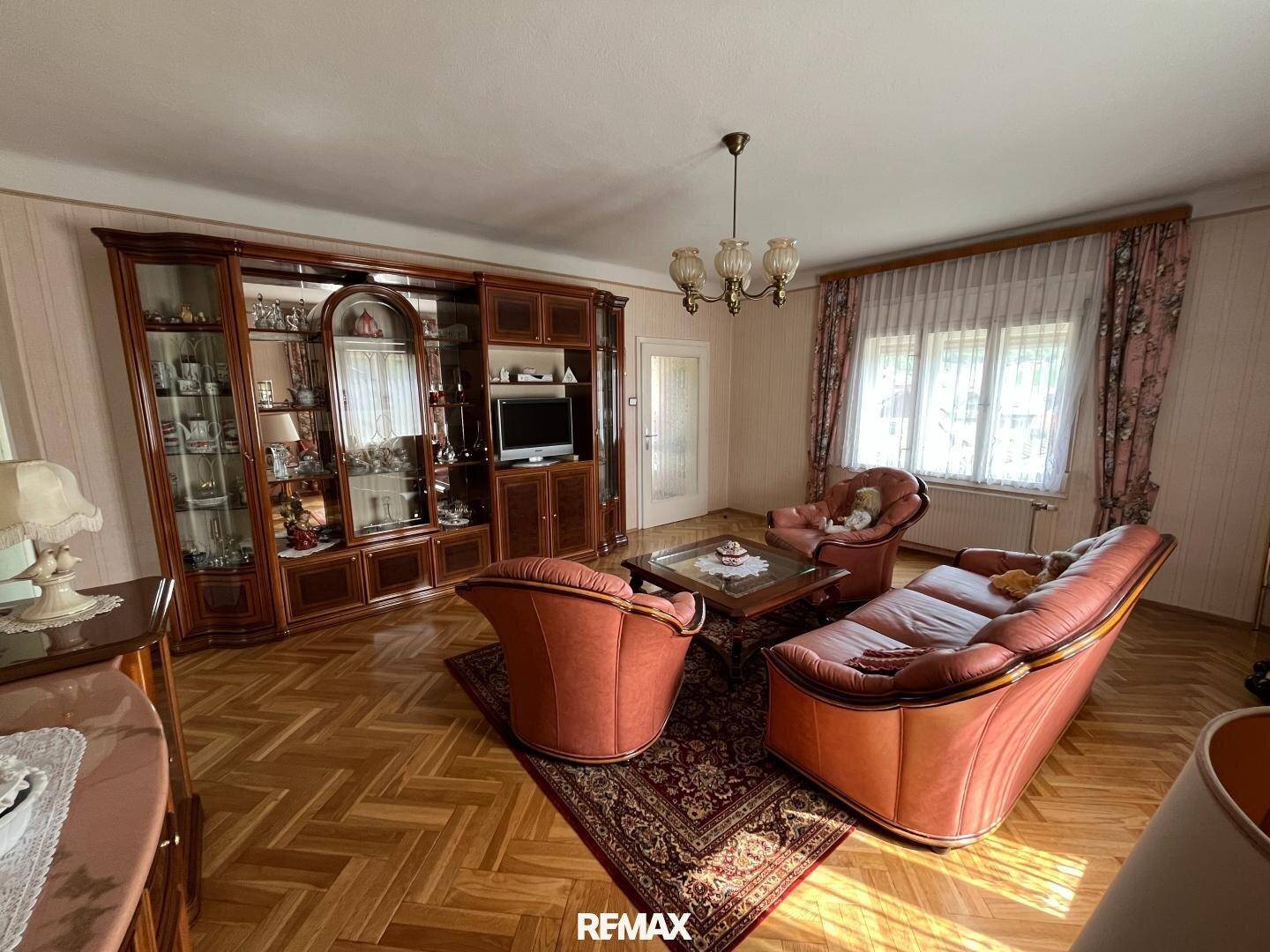 Traditionelles Wohnzimmer mit Holzparkett, großem Schrank und bequemen Ledersofas.