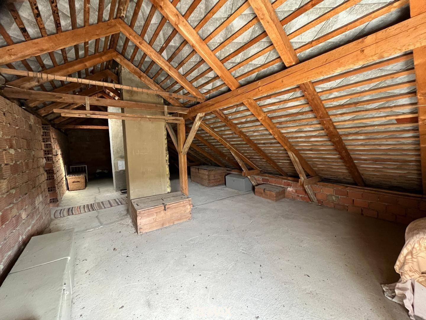 Geräumiger Dachboden mit Holzdachstuhl und Ziegelwänden, bereit für Ausbau.