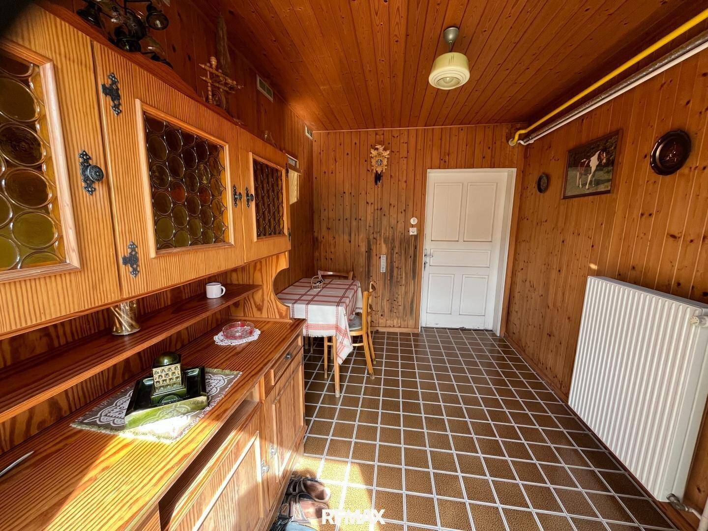 Rustikaler Raum mit Holztäfelung, Fliesenboden und kleinem Esstisch in traditionellem Stil.