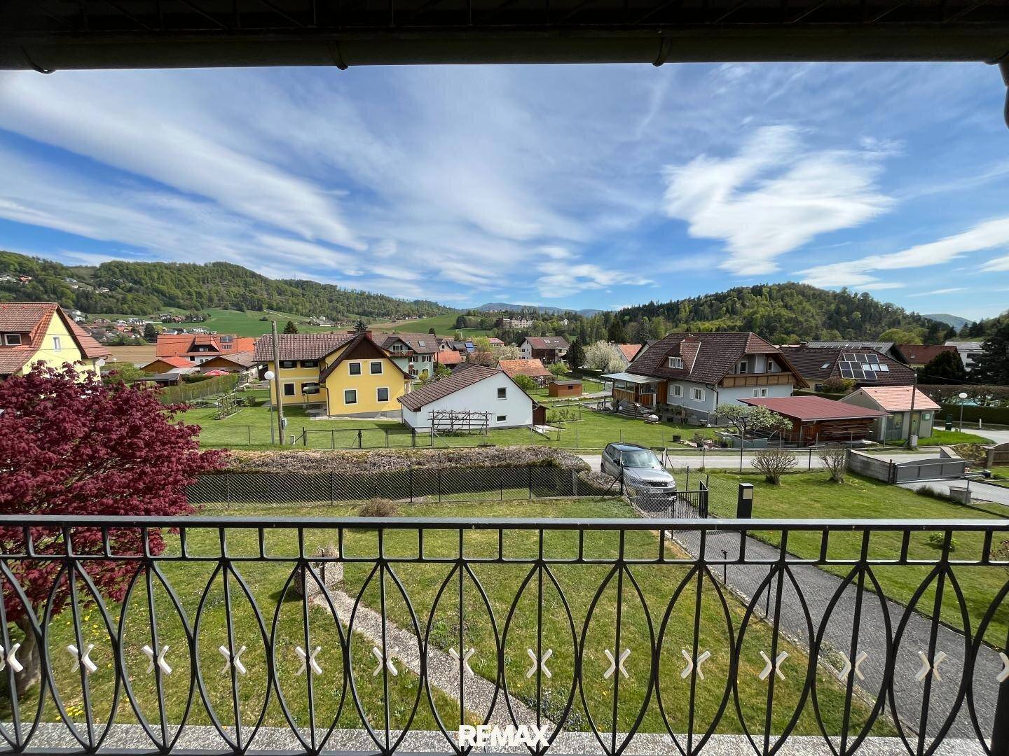 Balkon mit weitem Blick über die grüne Landschaft und die Nachbarschaft unter blauem Himmel.