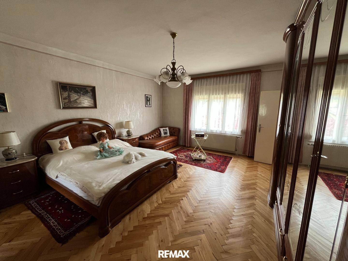 Helles Schlafzimmer mit Holzparkett, großem Bett und Spiegelschrank in traditionellem Stil.
