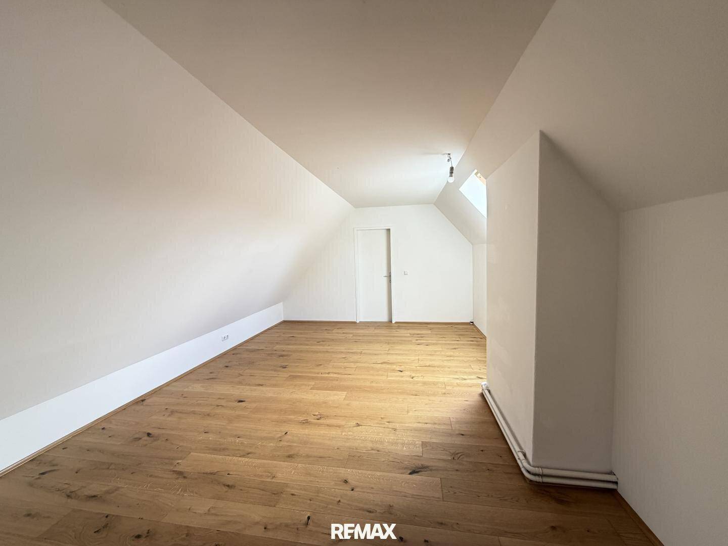 Dachgeschosszimmer mit Holzboden und weiß gestrichenen Wänden, bietet vielseitige Nutzungsmöglichkeiten.