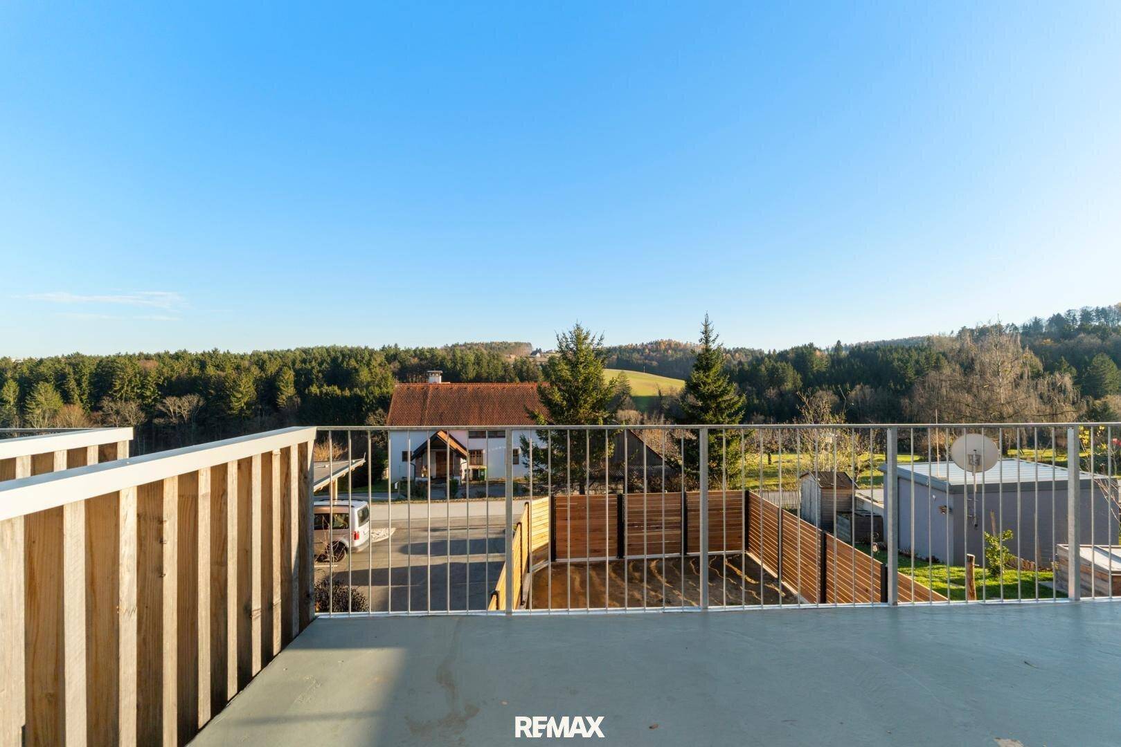 Balkon mit Weitblick über die ländliche Umgebung und bewaldete Hügel.