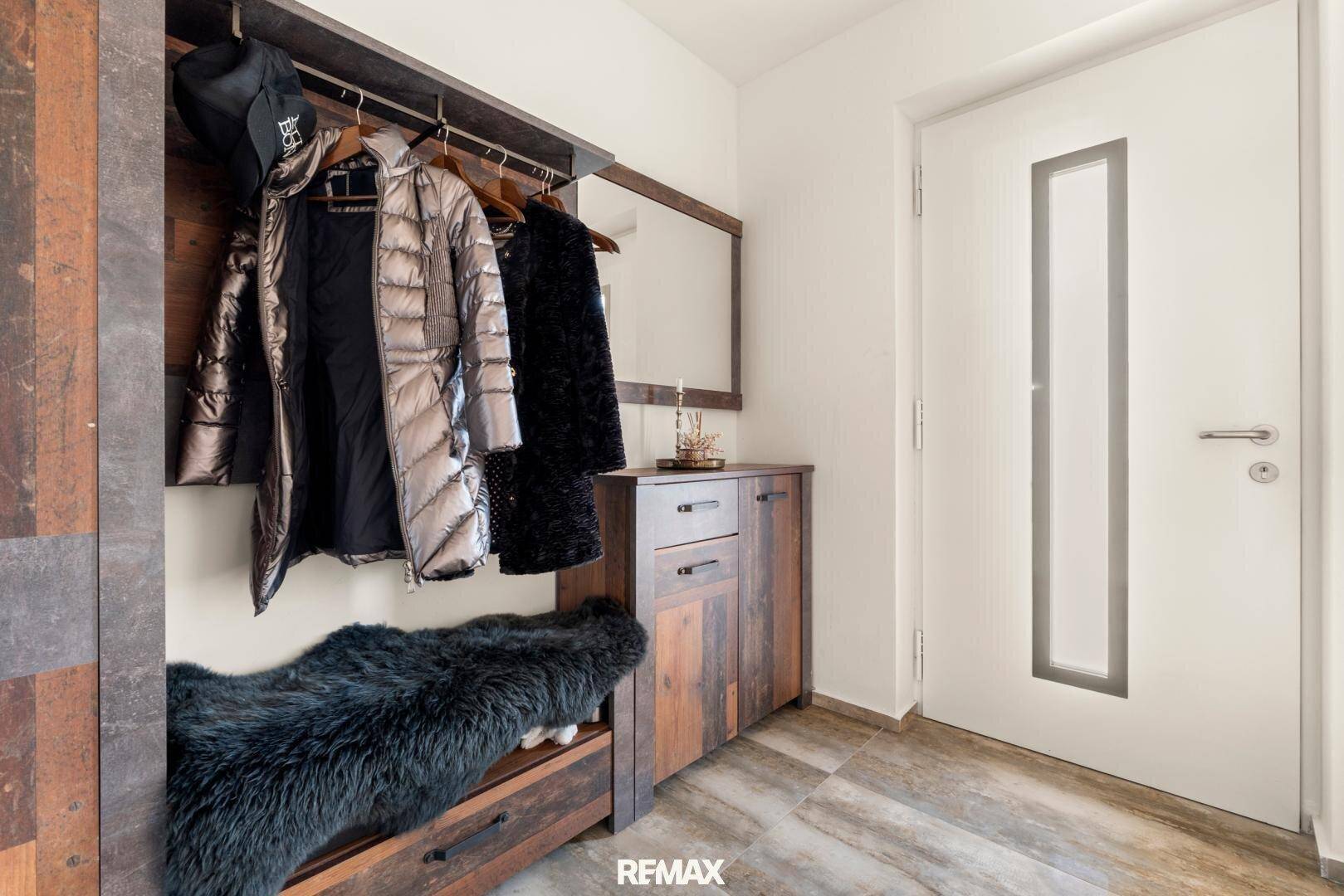 Eingangsbereich mit Garderobe, Spiegel und rustikalen Holzmöbeln für den Empfang.