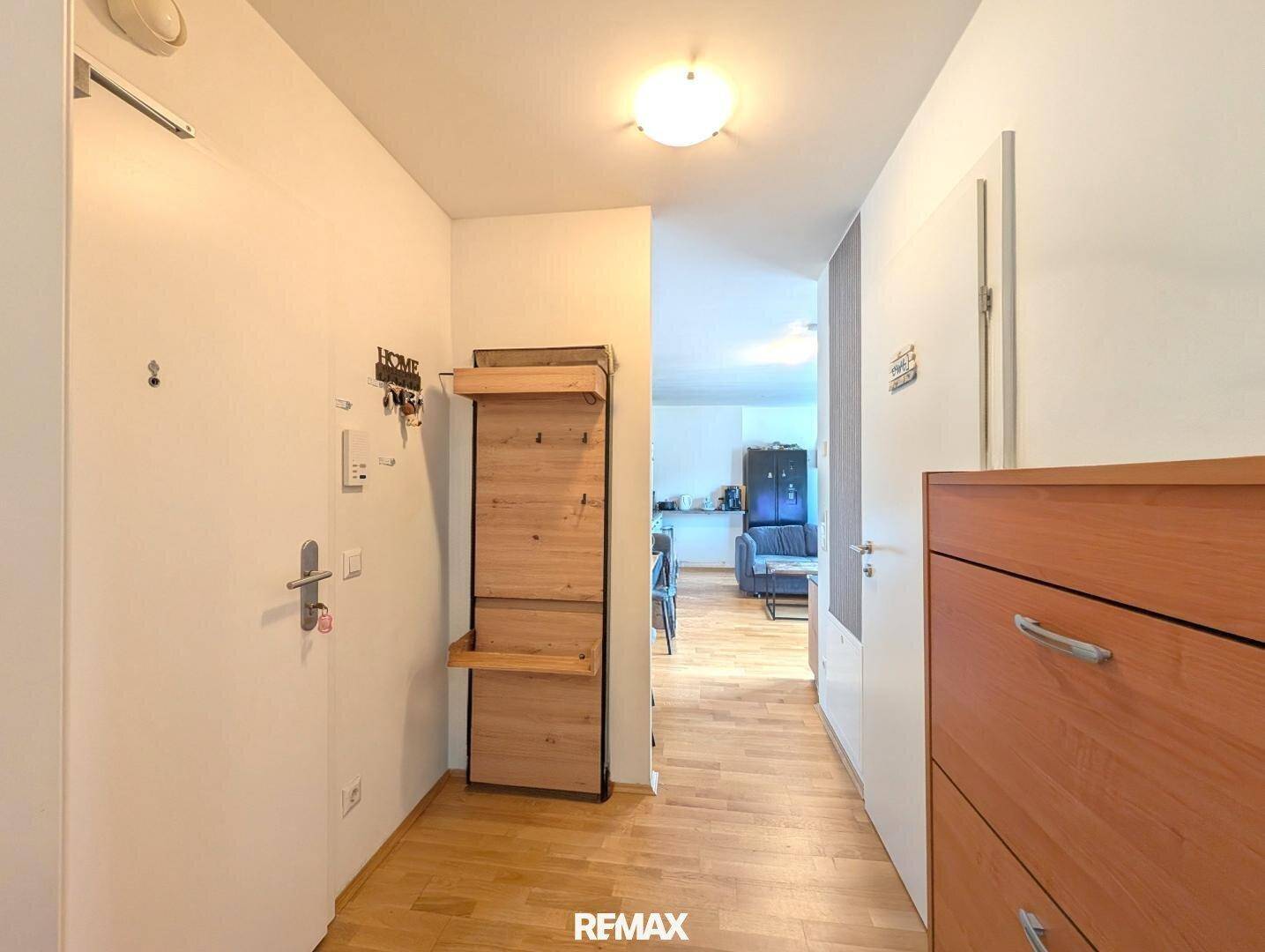 Heller Eingangsbereich mit Garderobe und Schuhschrank, der in den Wohnbereich führt.