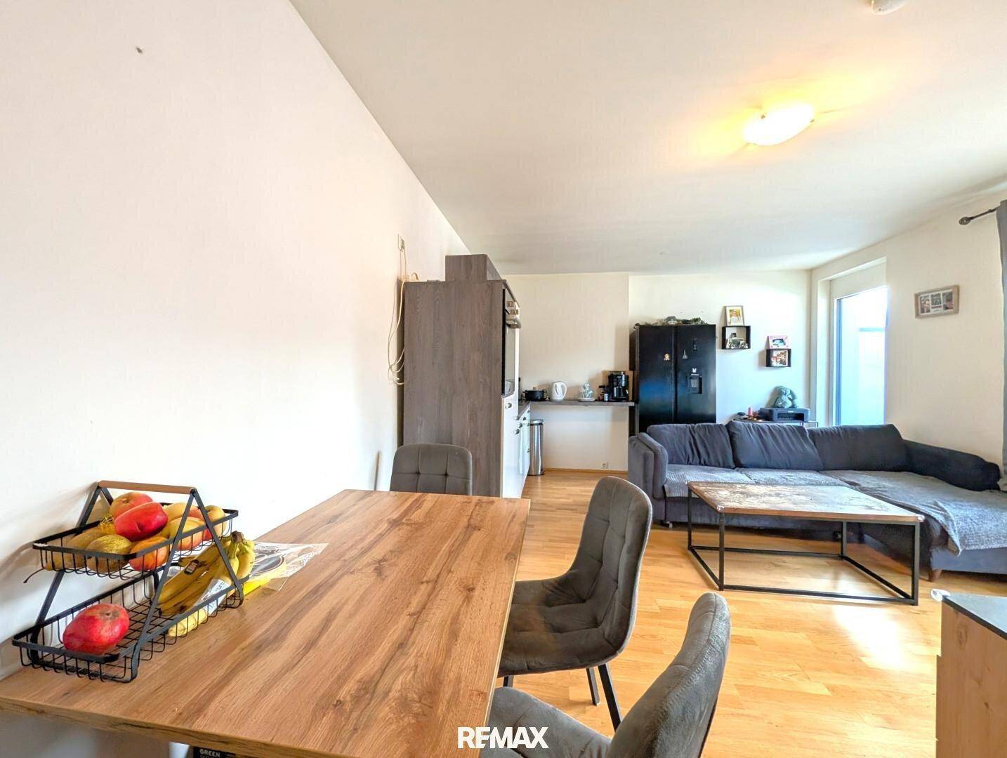 Offener Wohn- und Essbereich mit Holztisch, bequemen Stühlen und Blick auf die Küche.