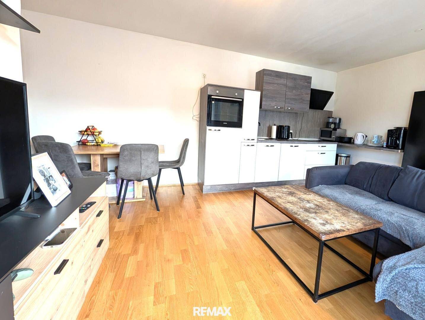 Moderne Einbauküche mit Backofen, Essbereich und offenem Übergang zum Wohnzimmer.